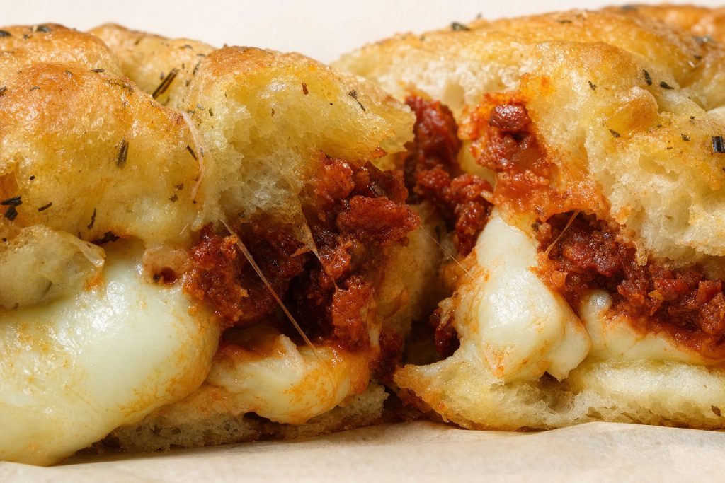 Extreme close-up — focaccia, torn open, visible fillings